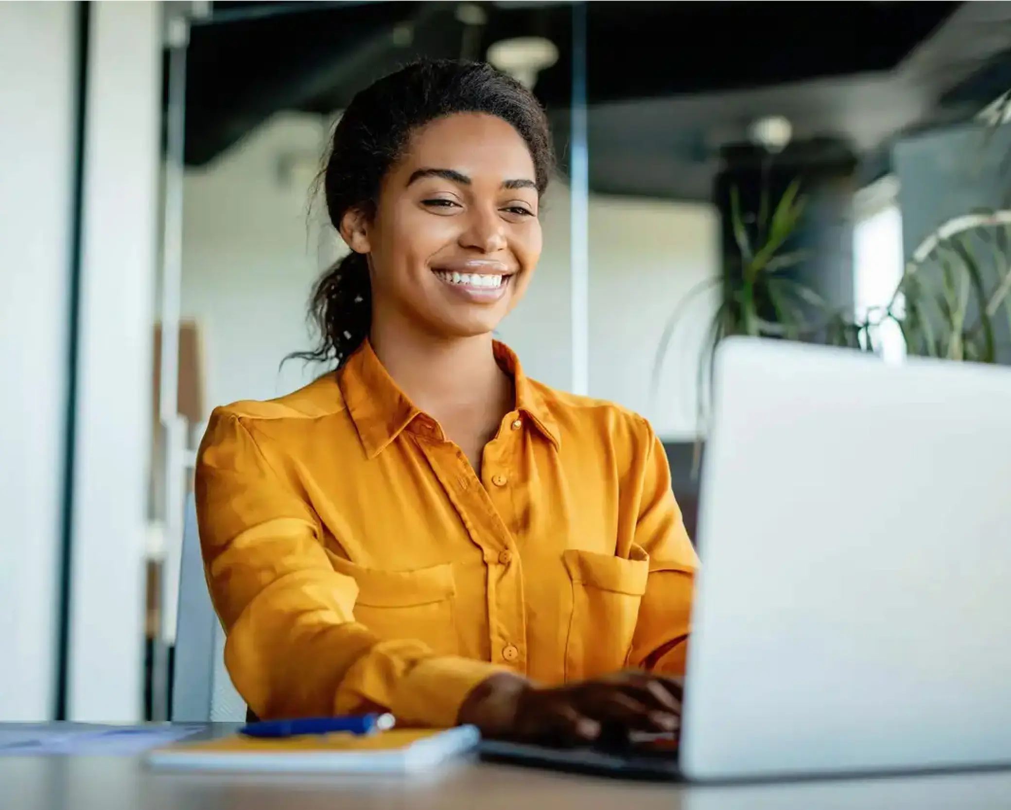 Woman in orange shirt smiling while working at workstation